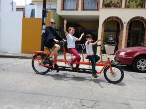 urban cycling mexico image showing a woman and two kids on a tandem